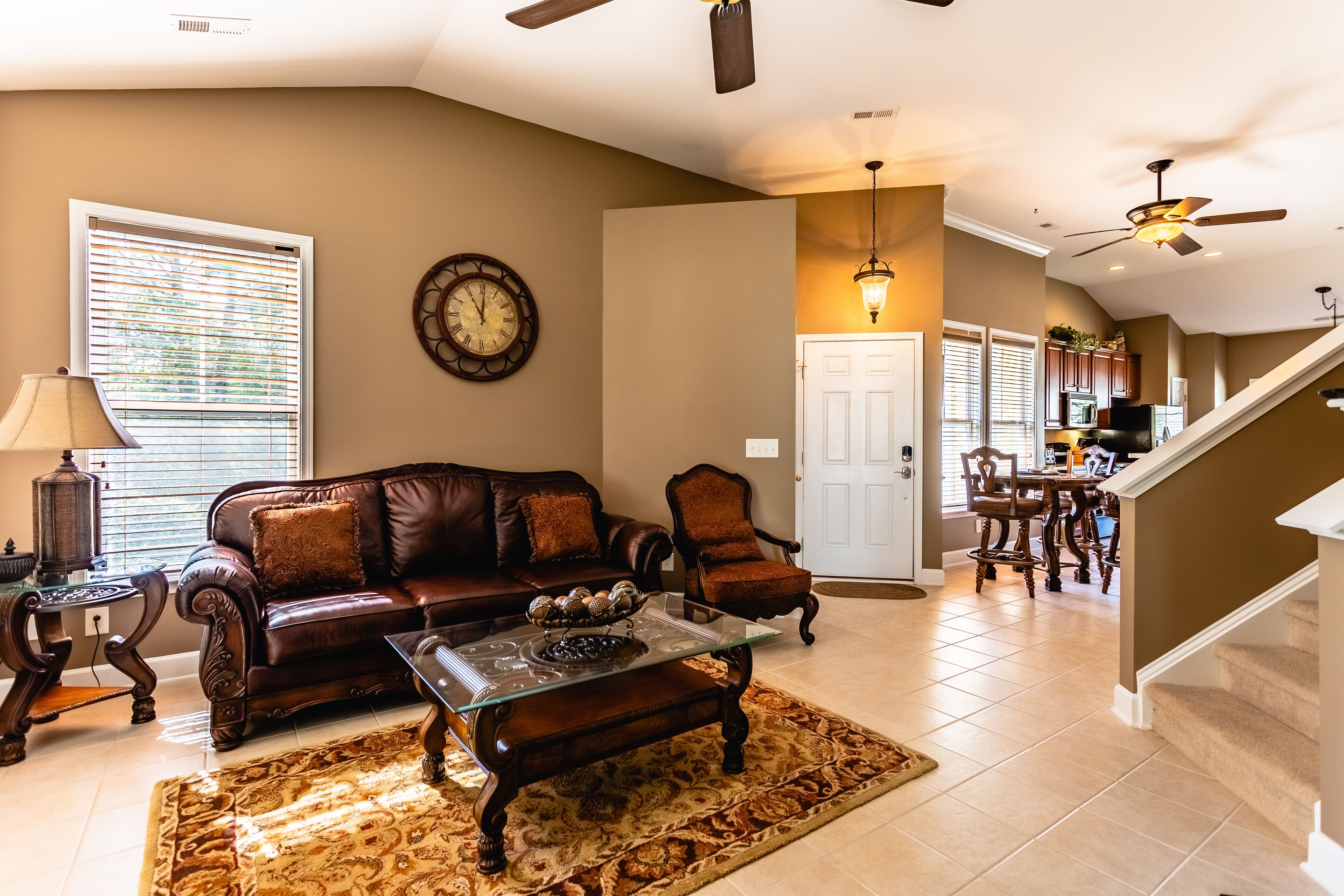 A spacious living room with a leather sofa, a glass coffee table, and a patterned rug.