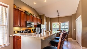 Una cocina con armarios de madera, encimera de granito y una barra con taburetes.
