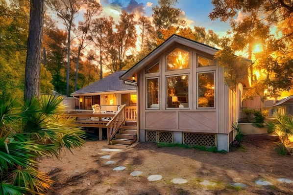A house with a deck, a staircase, and a view of trees.