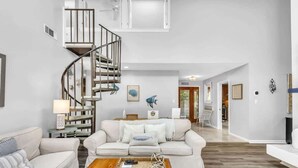 A modern living room with a spiral staircase, a sofa set, a coffee table, and artwork on the walls. - Stylish Sea Pines Home Hot Tub, Hilton Head (Hilton Head Island)