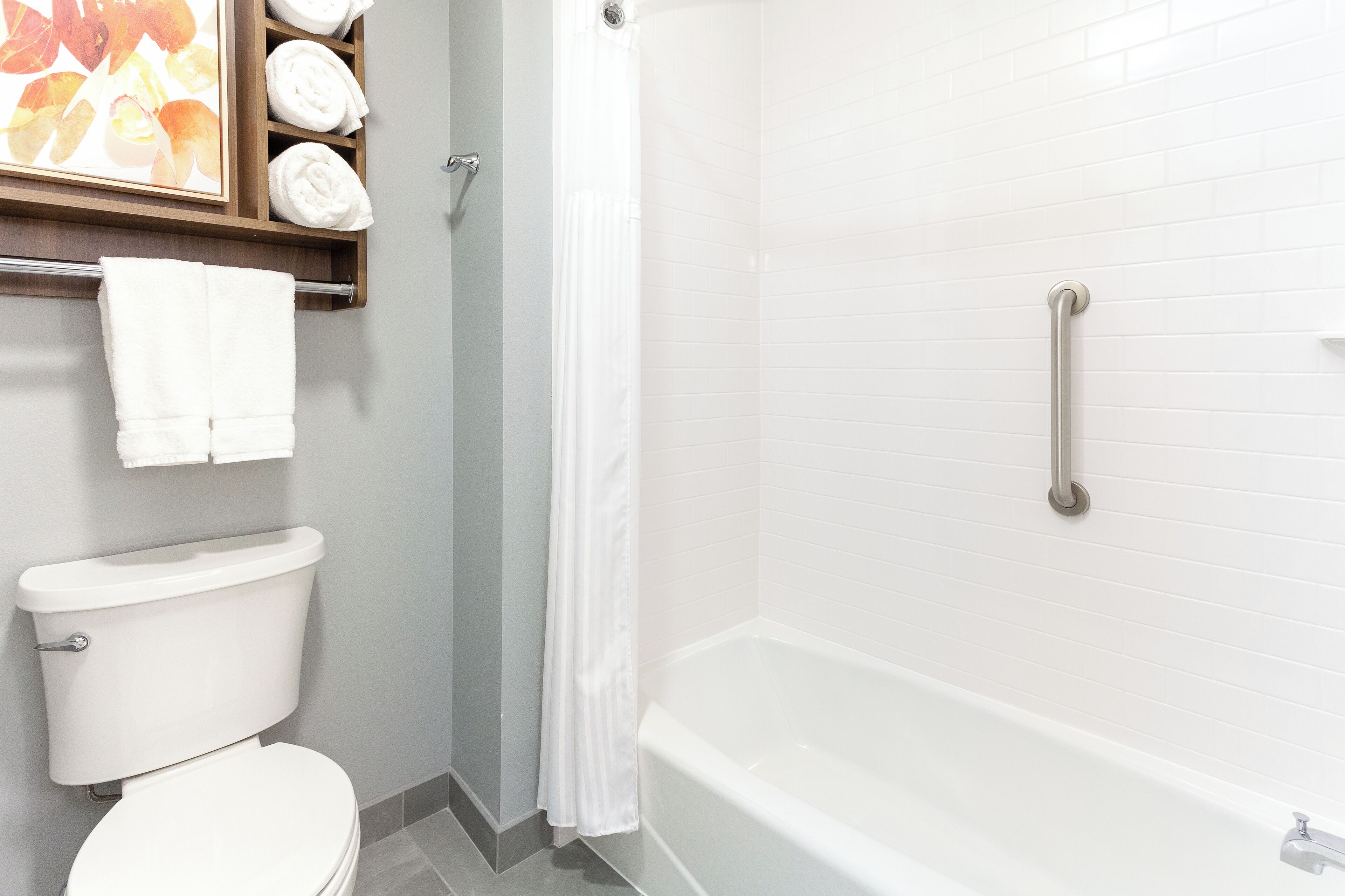 Ein Badezimmer mit Toilette, einer Dusche mit Glastür und einer Badewanne mit Haltegriff.