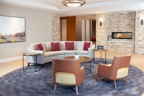 A modern hotel lobby with a sofa, two armchairs, a small table, and a fireplace. - Homewood Suites by Hilton Broomfield Boulder (Broomfield)