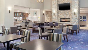 A hotel lobby with a dining area, bar, and kitchen in the background. - Homewood Suites by Hilton Broomfield Boulder (Broomfield)