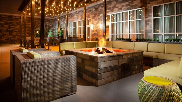 An outdoor seating area with a fire pit, wicker furniture, and a stone wall. - Homewood Suites by Hilton Broomfield Boulder (Broomfield)