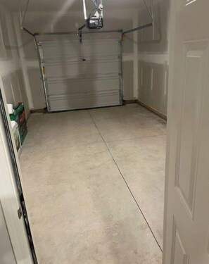 Garage with a closed metal door and a ceiling-mounted light fixture.
