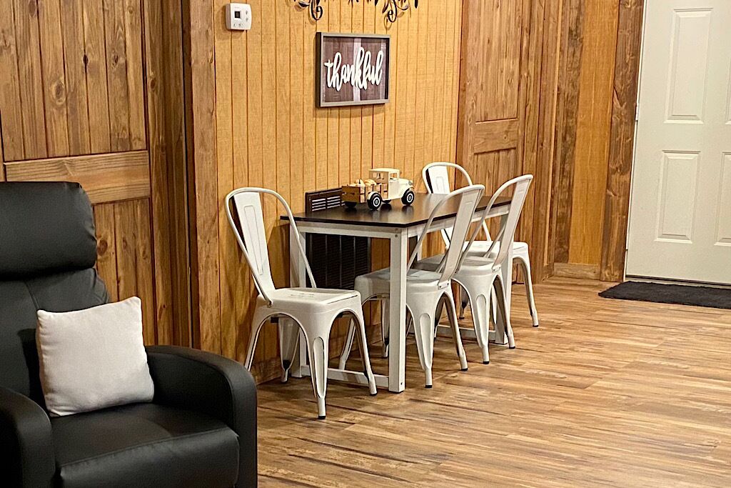 A dining area with a wooden wall, a table, and white chairs.