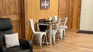 A dining area with a wooden wall, a table, and white chairs.
