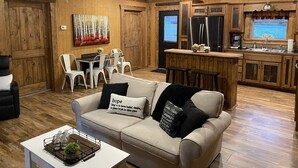 A cozy living room with a sofa, a coffee table, and a dining area with chairs and a table.