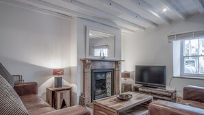 Een woonkamer met een open haard, leren banken, een houten salontafel en een televisie.