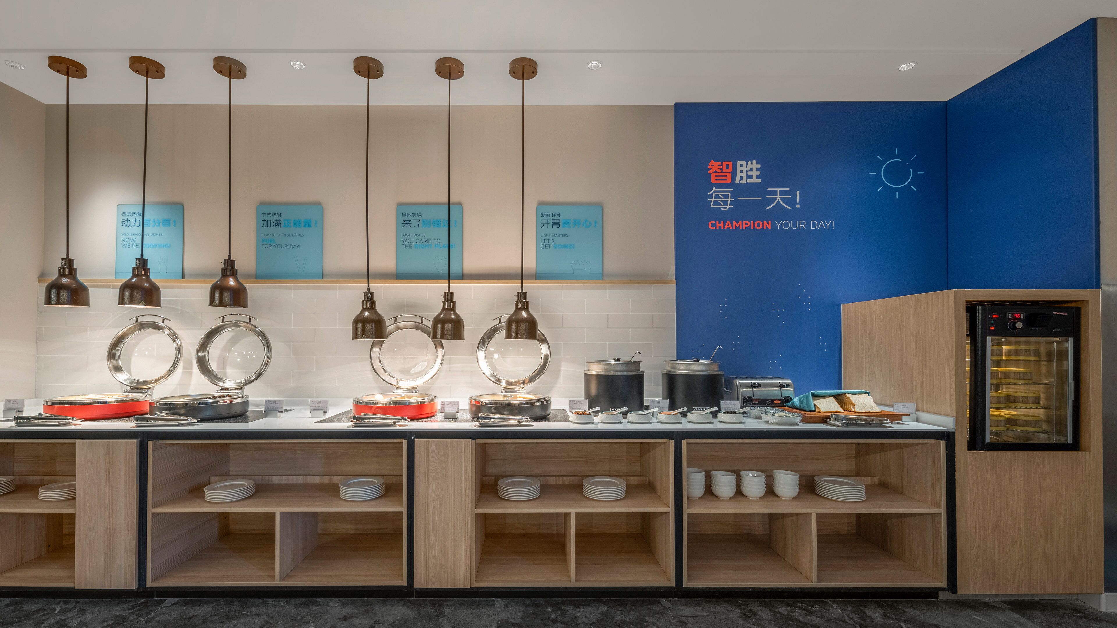 A kitchen area with hanging pendant lights, a blue wall with motivational text, and a refrigerator.