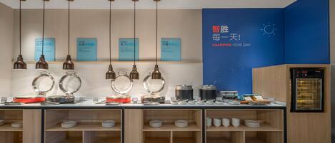 A kitchen area with hanging pendant lights, a blue wall with motivational text, and a refrigerator.