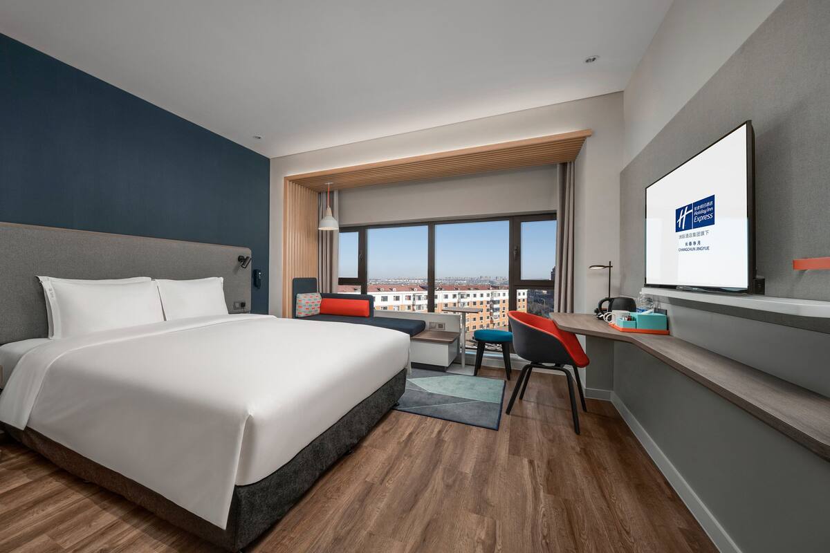 Une chambre d’hôtel moderne avec un grand lit, un bureau et une vue sur la ville.