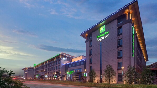 Un hotel Holiday Inn Express con diseño moderno, con varios pisos y un letrero llamativo.