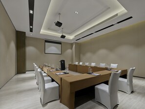 A conference room with a long table, chairs, a projector, and a screen. - DoubleTree by Hilton Quzhou (Quzhou)