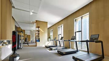 Un gimnasio con cintas de correr, un saco de boxeo y un estante fijado a la pared.
