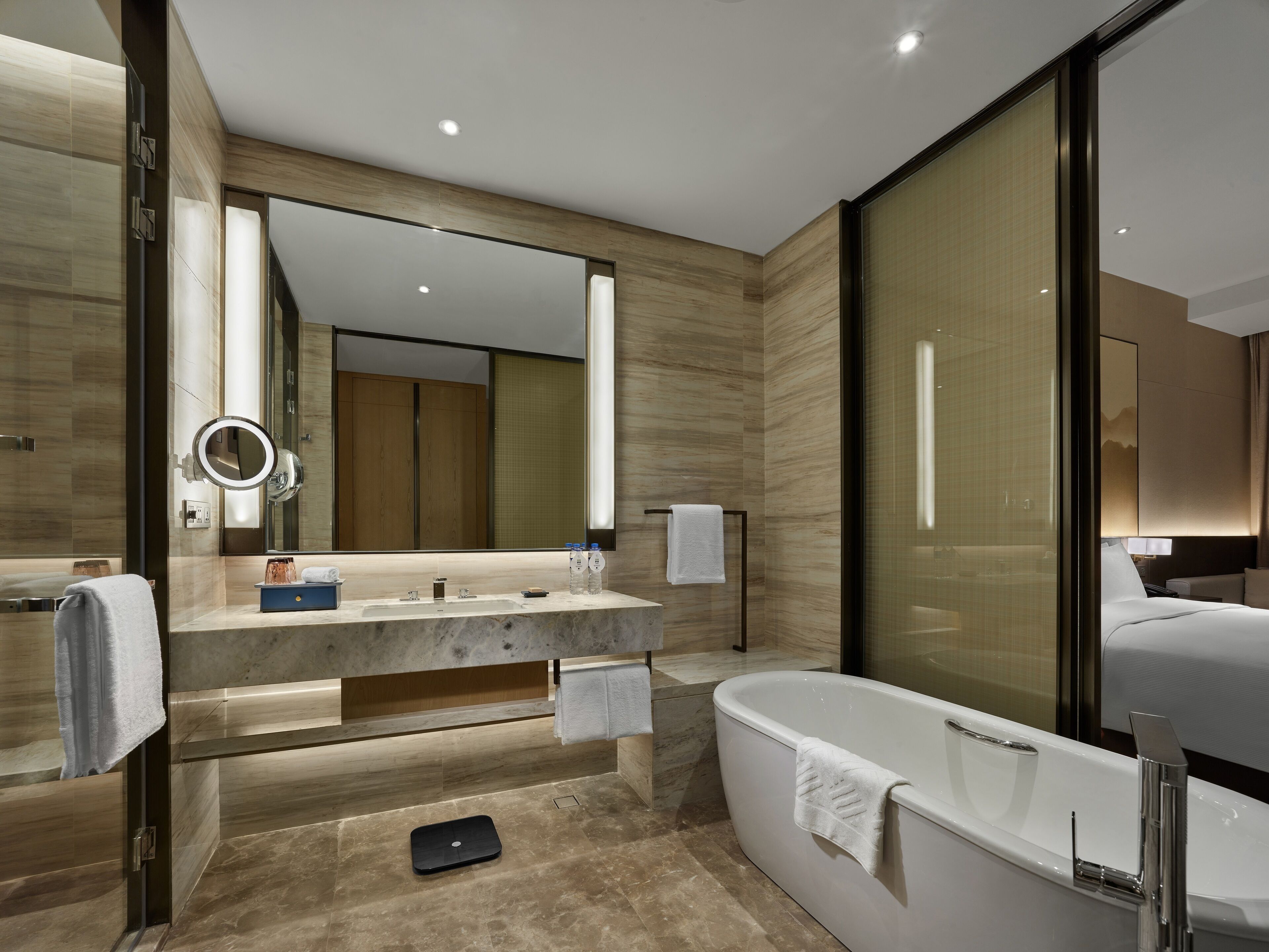 A modern bathroom with a large mirror, a vanity with a sink, a bathtub, and a scale.