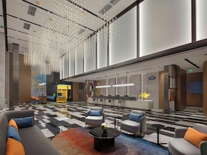 A modern lobby with a check-in counter, seating area, and decorative lighting.
