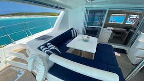 Ein Bootsdeck mit Sitzgelegenheit, einem kleinen Tisch und Blick auf das Meer.