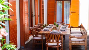 Una mesa de comedor de madera dispuesta con sillas, rodeada de puertas de madera con ventanas persianas.