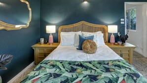 A bedroom with a large bed, two bedside tables, a mirror, and a window.