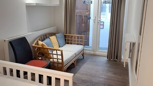Ett rum med en säng, en soffa, ett trägolv, en taklampa och en dörr med en skylt.