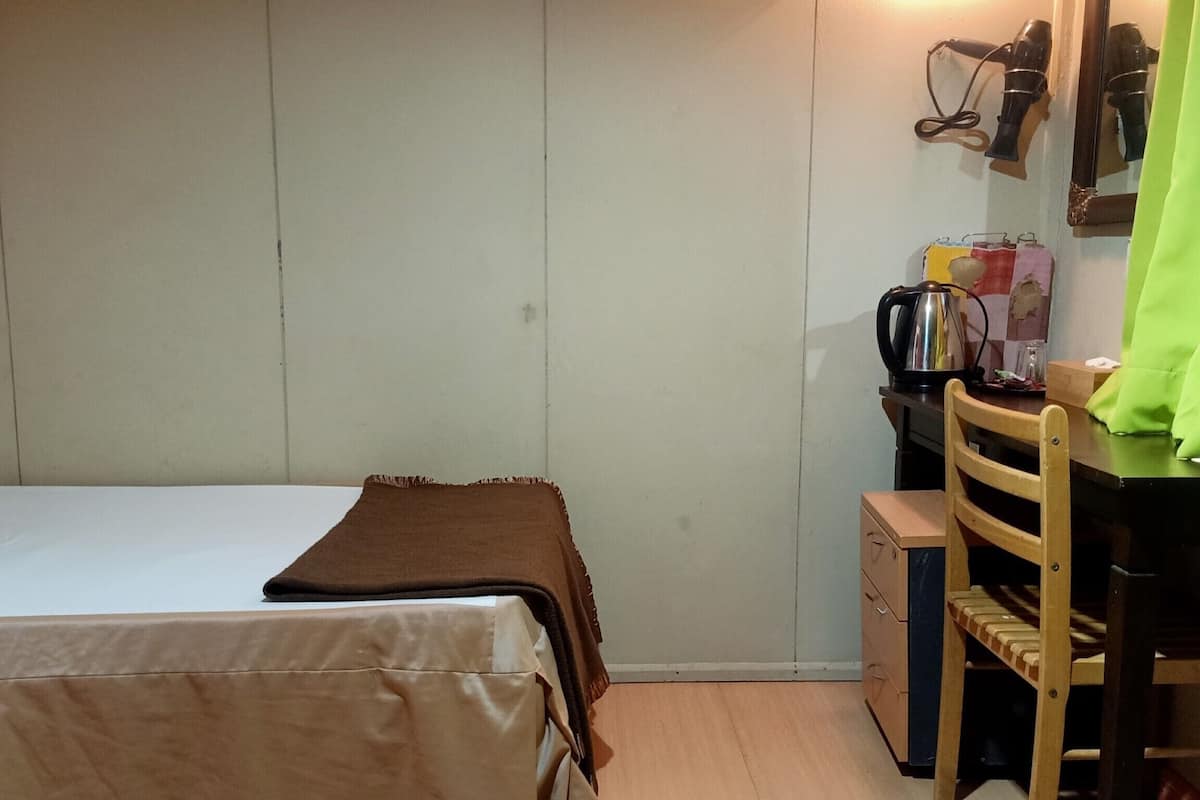Une chambre à coucher avec un lit, un bureau, une chaise et un miroir.