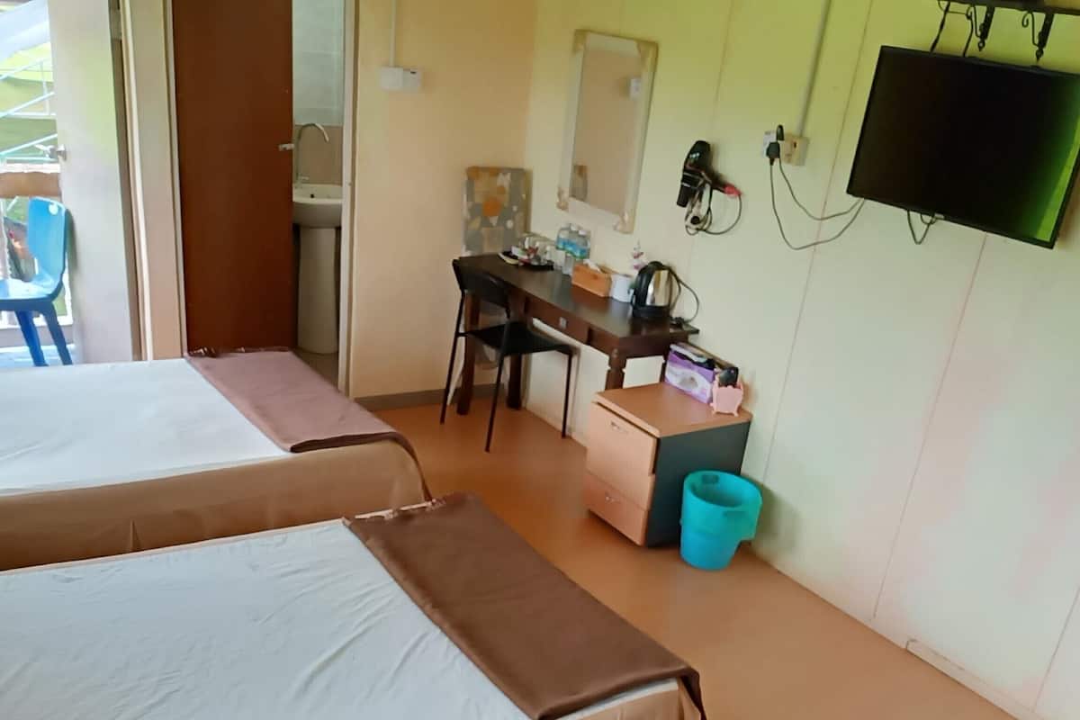 Une chambre d’hôtel avec deux lits, un bureau, une chaise, une télévision et une poubelle.