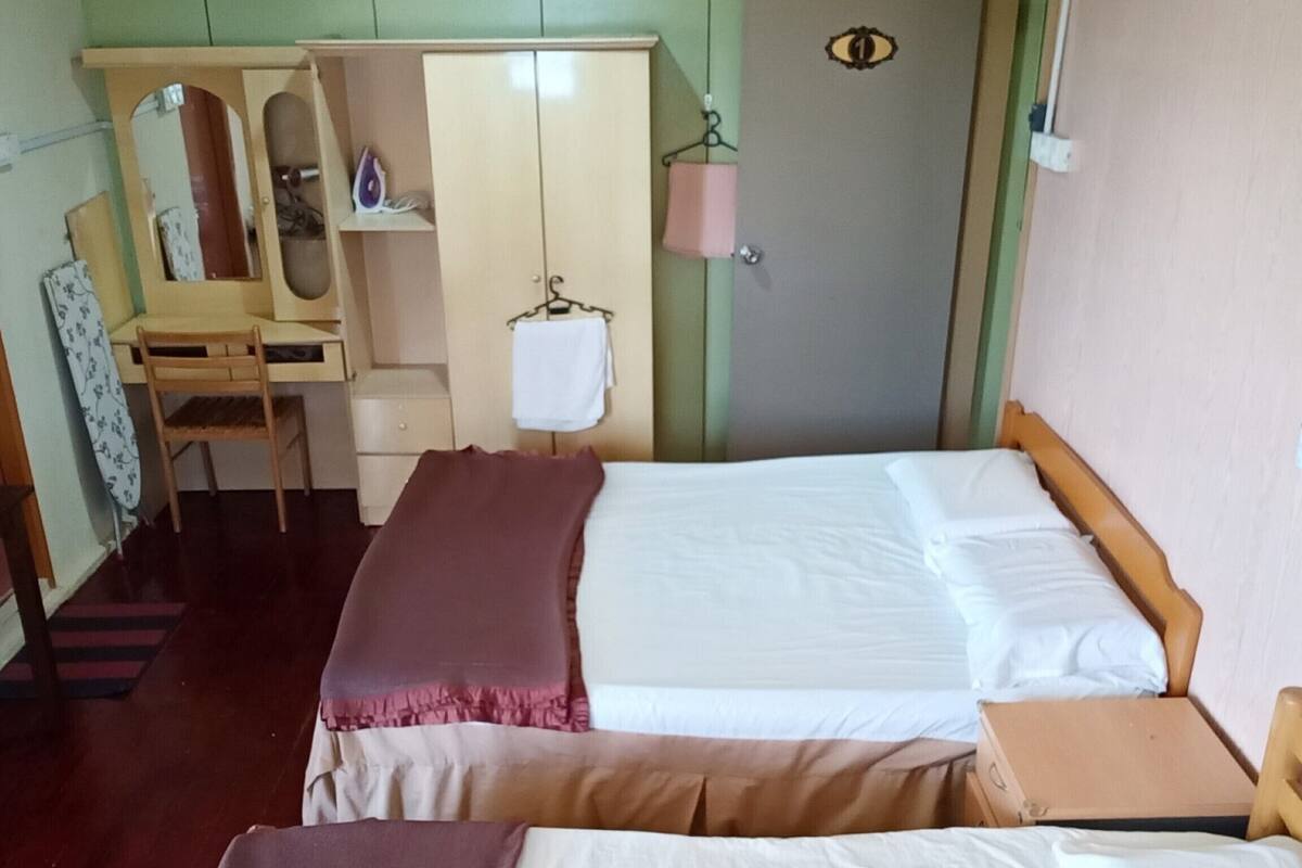Une chambre avec deux lits, un bureau, une armoire et un miroir.
