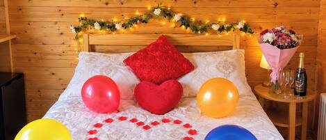 A bedroom with a bed, a bouquet of flowers, a bottle of champagne, and a banner that reads 'JUST MARRIED'.