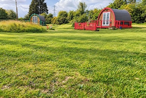 A grassy field with a red barn and a smaller blue structure.