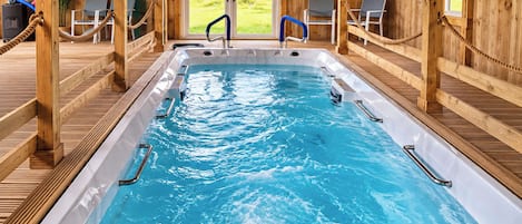 A hot tub with wooden railings and a view of greenery outside.