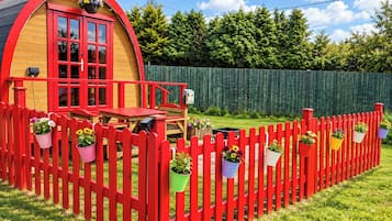 Ein kleines, rotes Holzgebäude mit Veranda und einem eingezäunten Garten.
