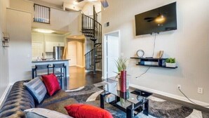 A modern living room with a sofa, coffee table, and a TV mounted on the wall. - Gorgeous downtown loft  (Dallas)