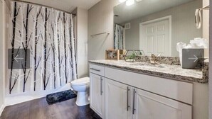 A bathroom with a toilet, vanity, and a shower curtain with a tree pattern. - Gorgeous downtown loft  (Dallas)