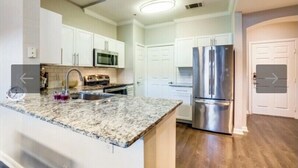 A modern kitchen with white cabinets, stainless steel appliances, and a granite countertop. - Gorgeous downtown loft  (Dallas)