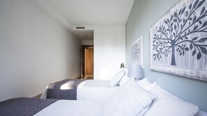 Habitación de hotel con dos camas, un ventanal grande y obras de arte en la pared.
