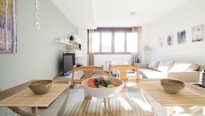 Una sala de estar moderna con una mesa de centro de vidrio, un sofá y un televisor.