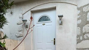Eine weiße Tür mit einem kleinen Fenster darüber, begleitet von zwei Wandleuchten.