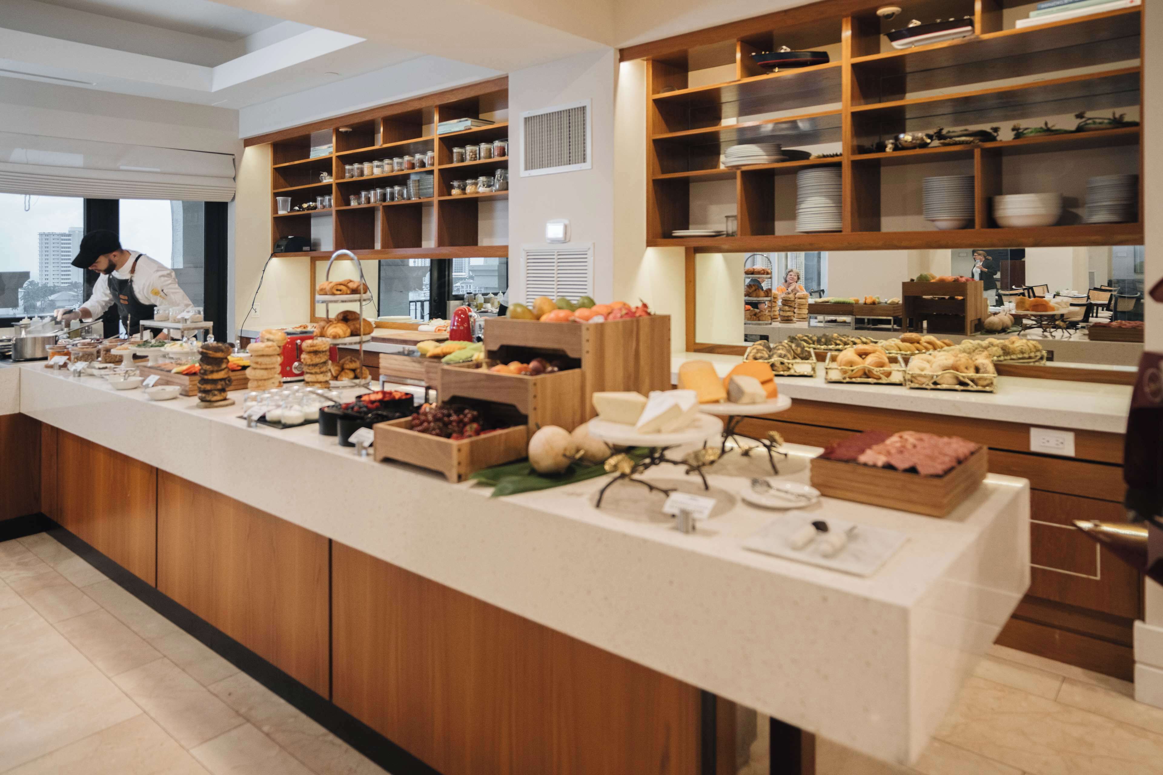 A buffet setup with various food items and a person serving.