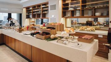 A buffet setup with various food items and a person serving.