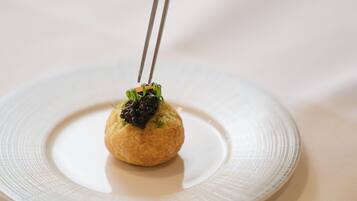 A round plate with a small, round food item on top, held by chopsticks.
