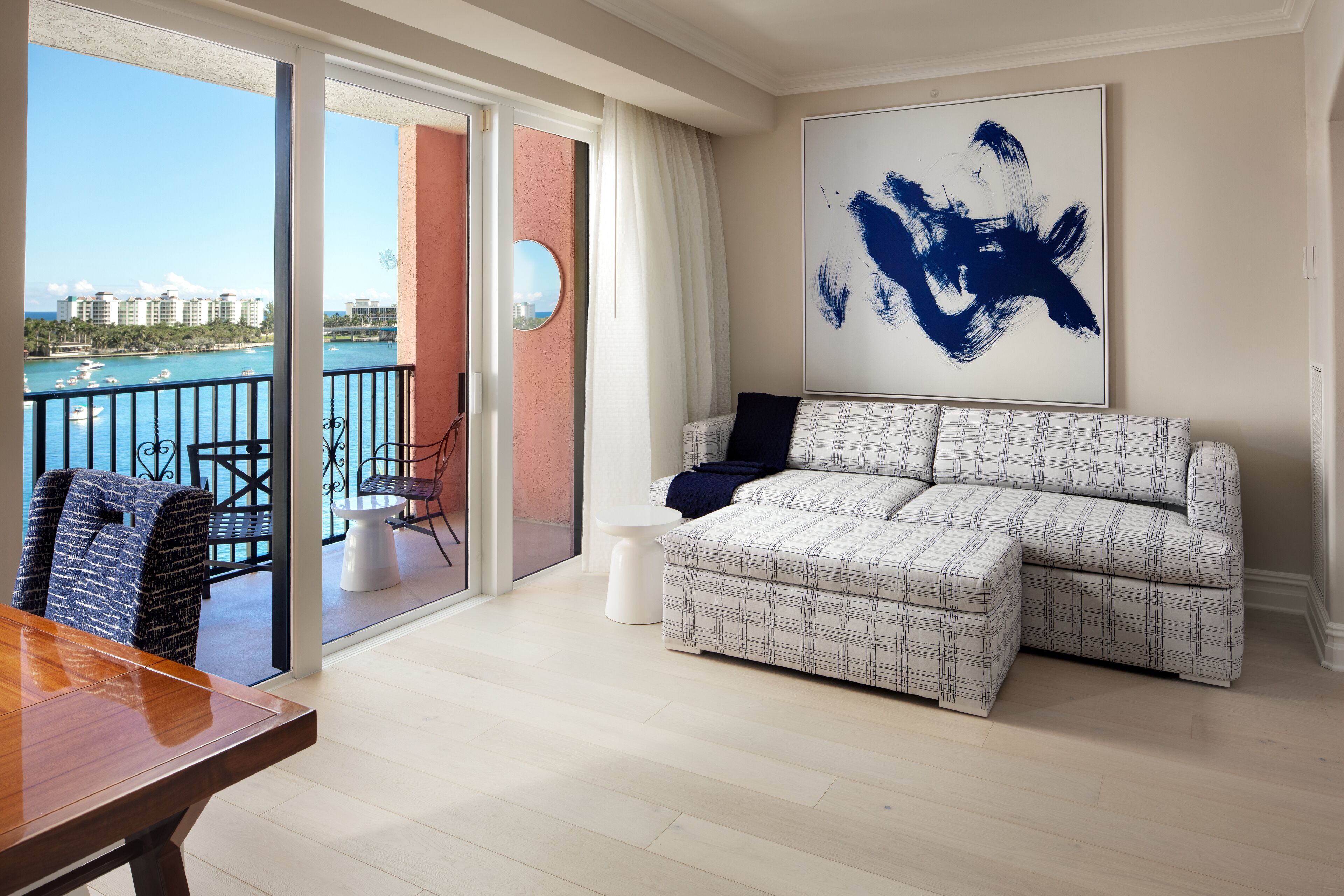 A living room with a large window, a sofa, a coffee table, and a view of the ocean.