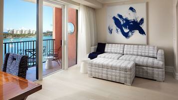A living room with a large window, a sofa, a coffee table, and a view of the ocean.