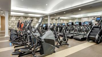 A gym with multiple treadmills and elliptical machines, a patterned wall, and a modern ceiling design.