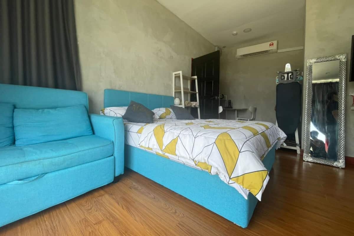 A bedroom with a bed, a blue sofa, a mirror, and a wardrobe.