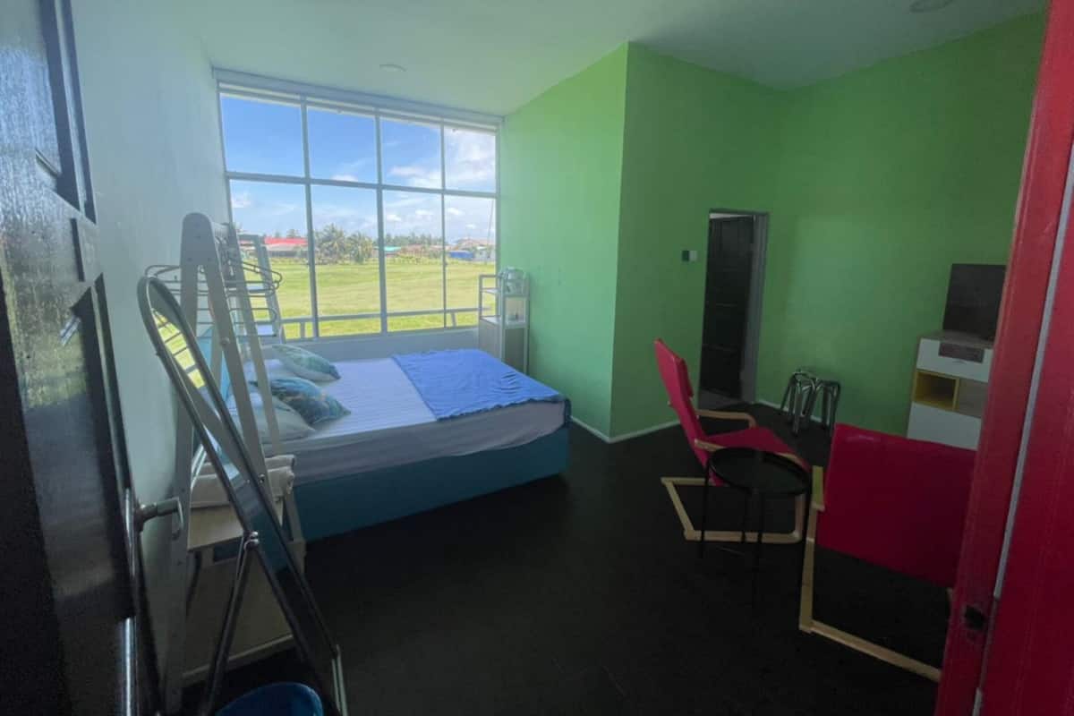 A room with a bed, a window, a chair, and a desk.