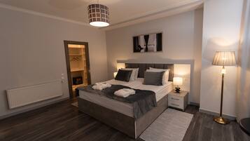 Een moderne slaapkamer met een groot bed, nachtkastjes, een vloerlamp, een radiator en een inloopkast.
