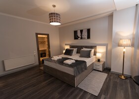Een moderne slaapkamer met een groot bed, nachtkastjes, een vloerlamp, een radiator en een inloopkast.