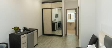 A hotel room with a bed, bedside table, desk, and a mirror.