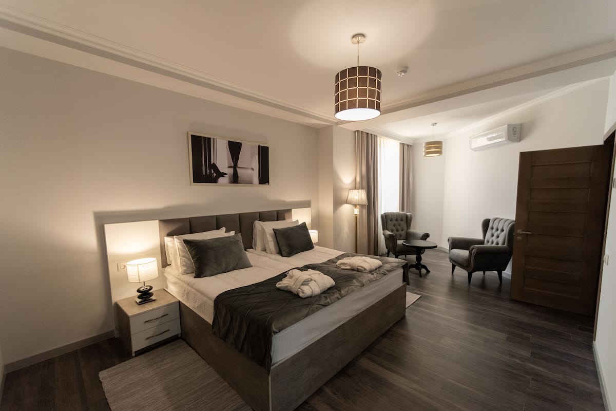 A modern hotel room with a large bed, bedside tables, a desk, and a chair.